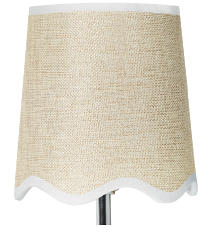 Silver wall sconce with beige shade on white wall.