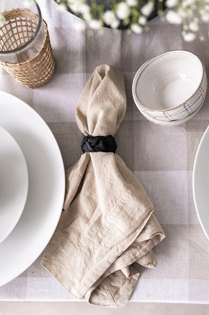 Black braided leather napkin ring wrapped around a linen napkin