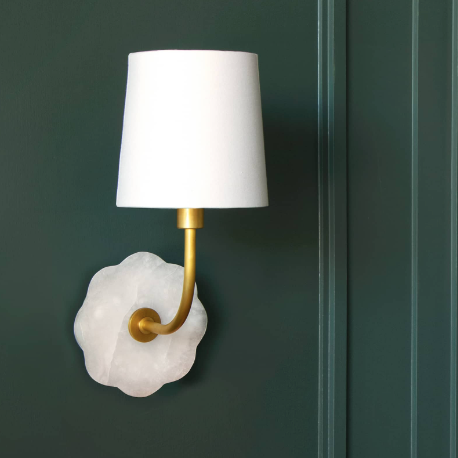 Brass and alabaster wall sconce with white shade on green wall.