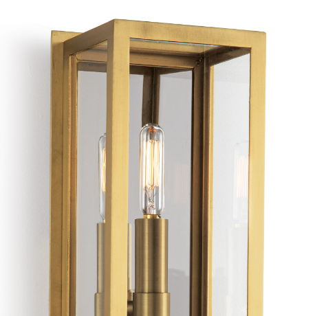 Natural brass sconce with lights on white wall.