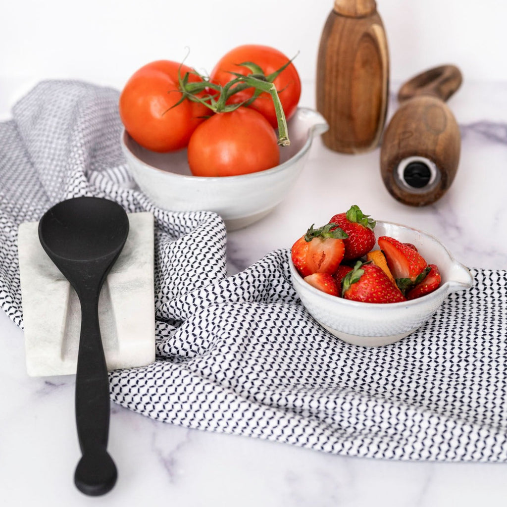 black and white stripe tea towel with strawberries an d tomatoes on marble countertop 