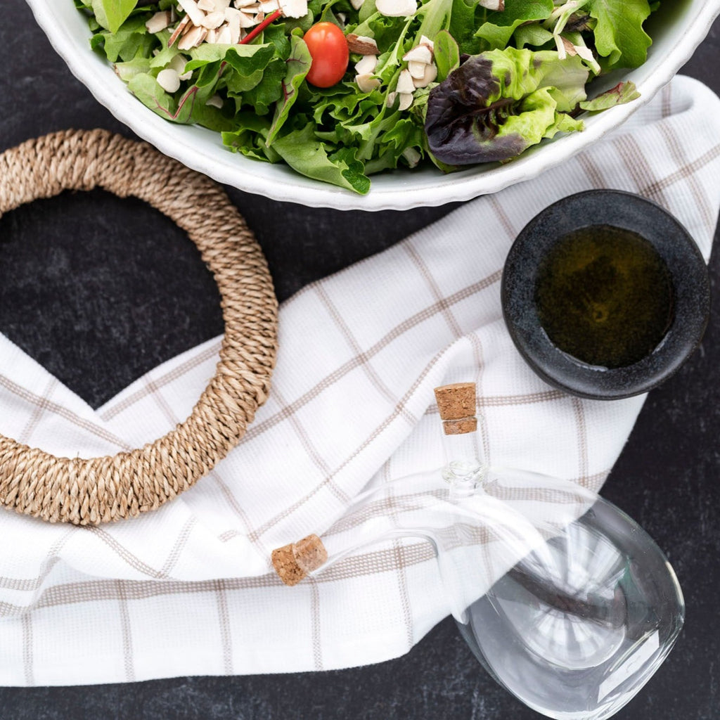 Linen Dish Towel next to bowl  of salad and oil with black background