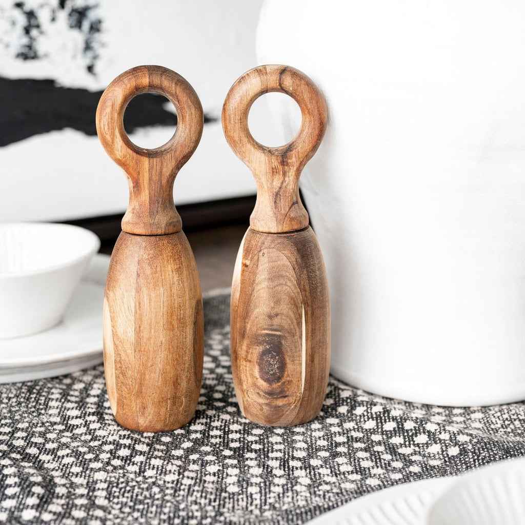 Wood salt and pepper grinders on back and whit table runner