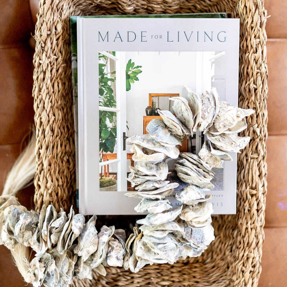 oyster shell decor garland on coofee tbale in a wicker basket on top of Amber Interiors book. Made for Living