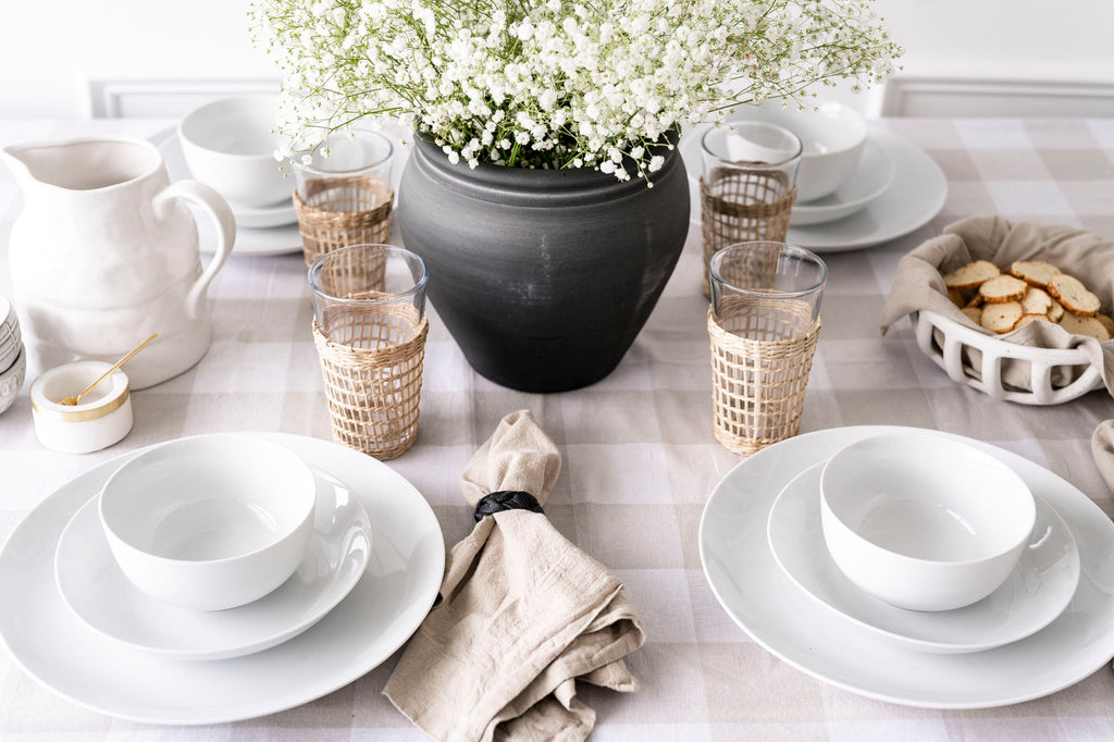 White dinnerware bowl styled with a black vase and table setting