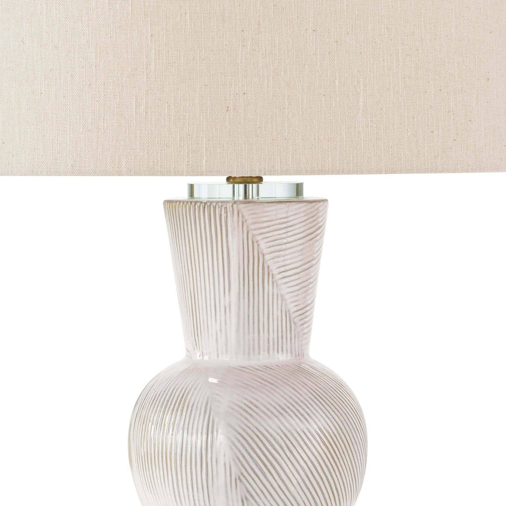White hugo ceramic table lamp in front of white wall.