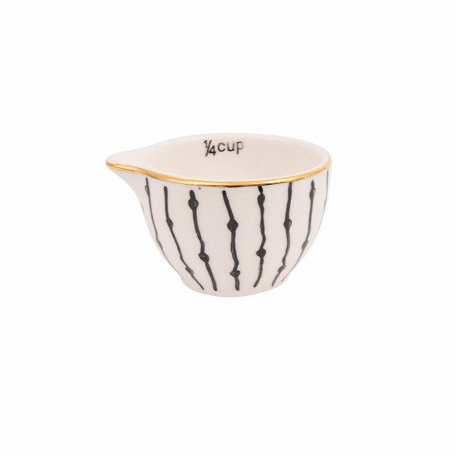 Black and white stoneware measuring cups with gold rim 1/4 cup on white background