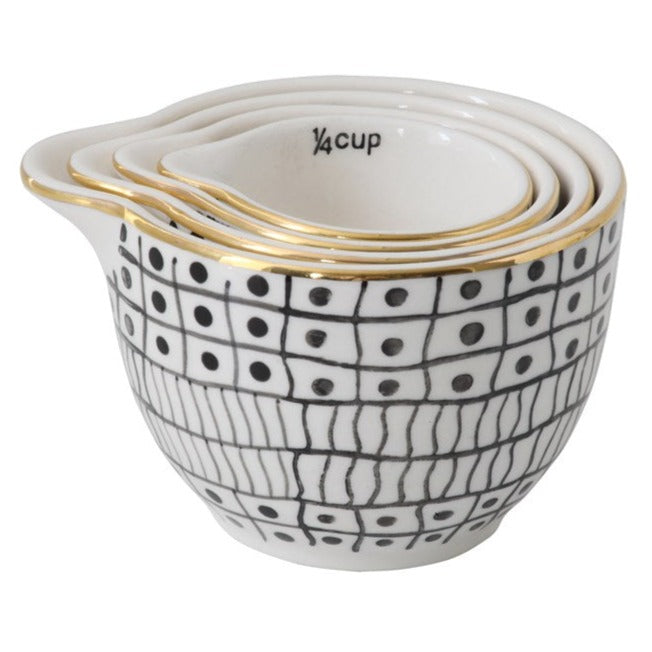 Black and white stoneware measuring cups with gold rim stacked inside each other  on white background